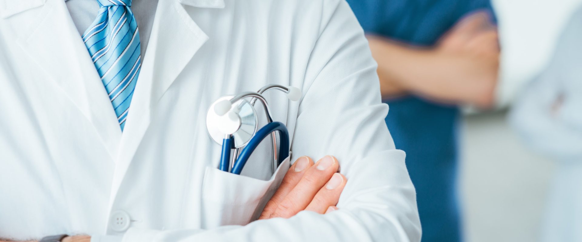 Professional medical team posing, doctor's lab coat and stethoscope close up, selective focus